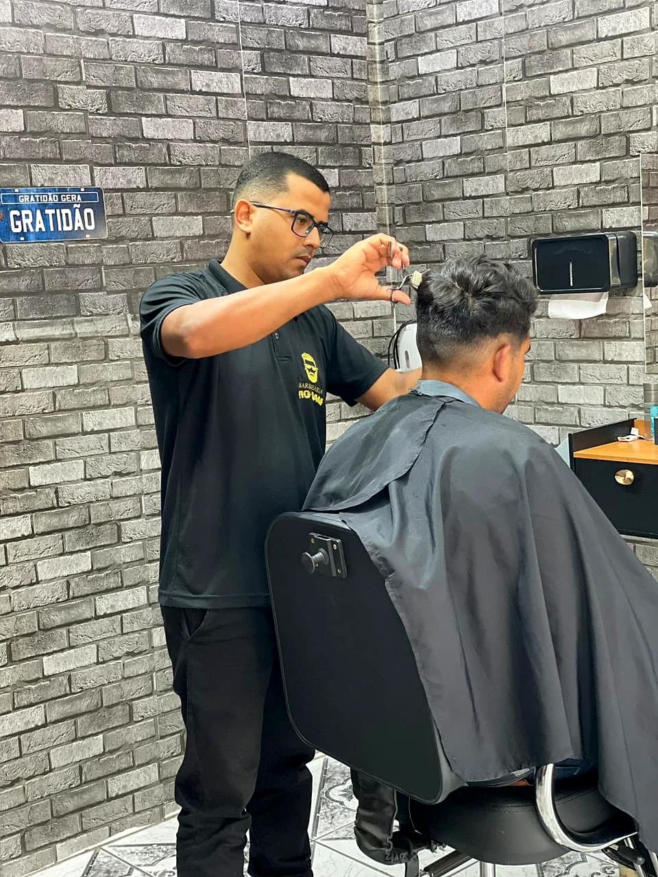 Barbeiro da Barbearia Tio Sam atendendo um cliente na cadeira